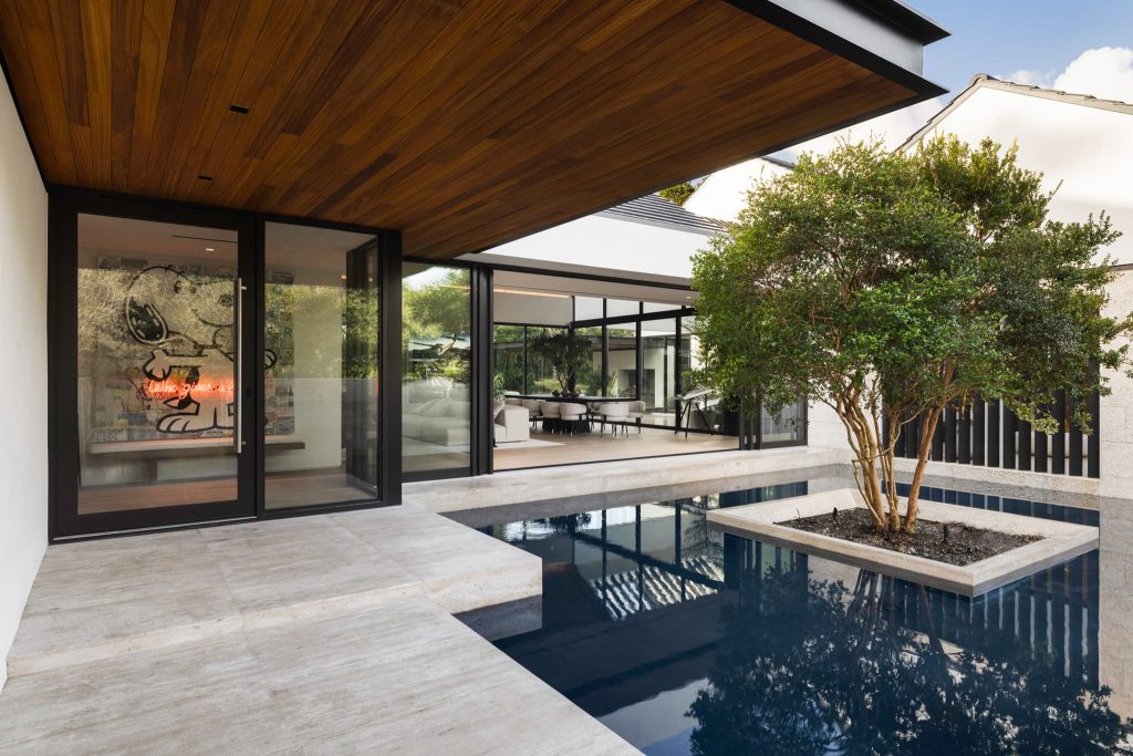 Modern contemporary home featuring an indoor pool, large glass windows, wood ceiling, and a central courtyard with a tree